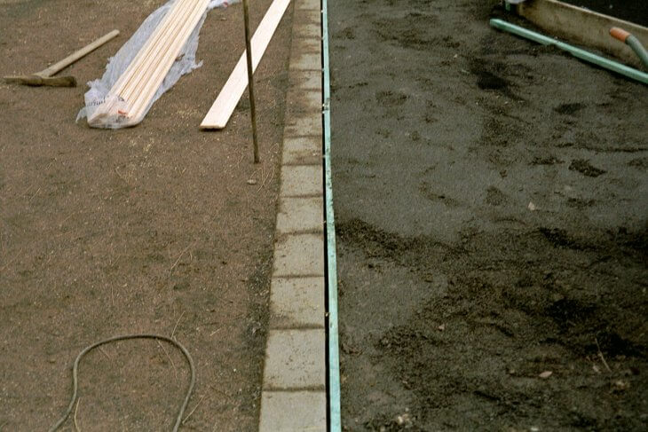 Eine Nahaufnahme des Übergangs der Grundierung des Teppichvlies in Mauersteine.