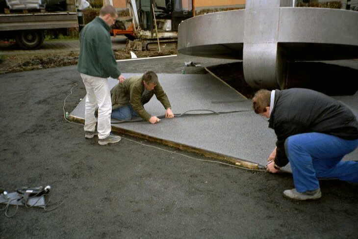 Drei Monteure arbeiten an der Randbegrenzung für das Teppichvlies.